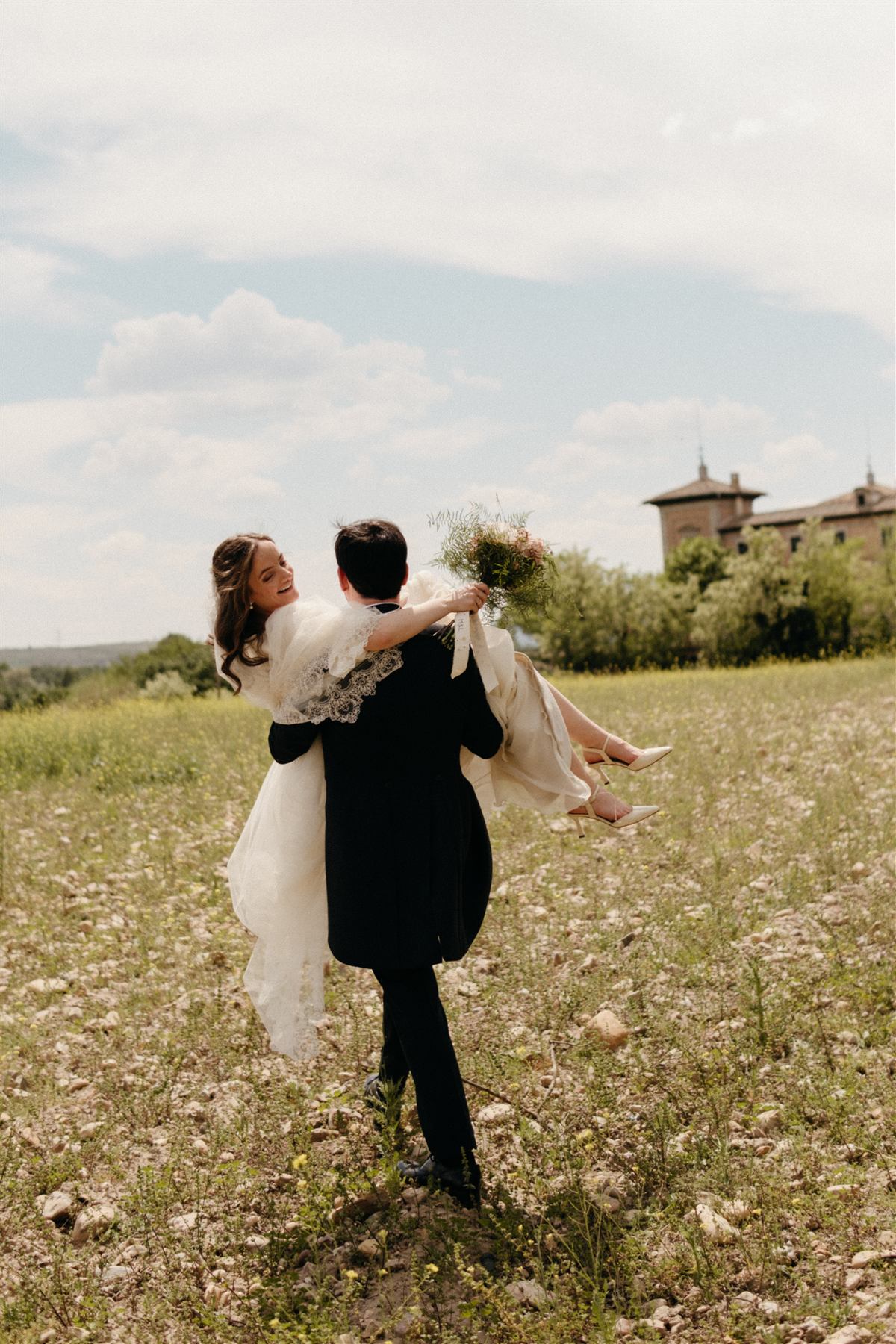 Novio llevando en brazos a la novia entre el campo